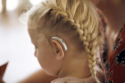Pige med fletning og høreapparat på venstre øre ses skråt bagfra