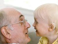 Bedstefar og lille dreng kigger hinanden i øjnene og griner
