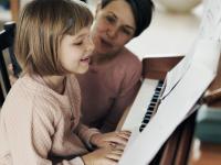 Mor og datter sidder ved klaveret og spiller