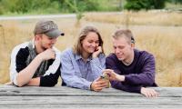 3 unge med høretab kigger på en mobiltelefon sammen og hygger sig